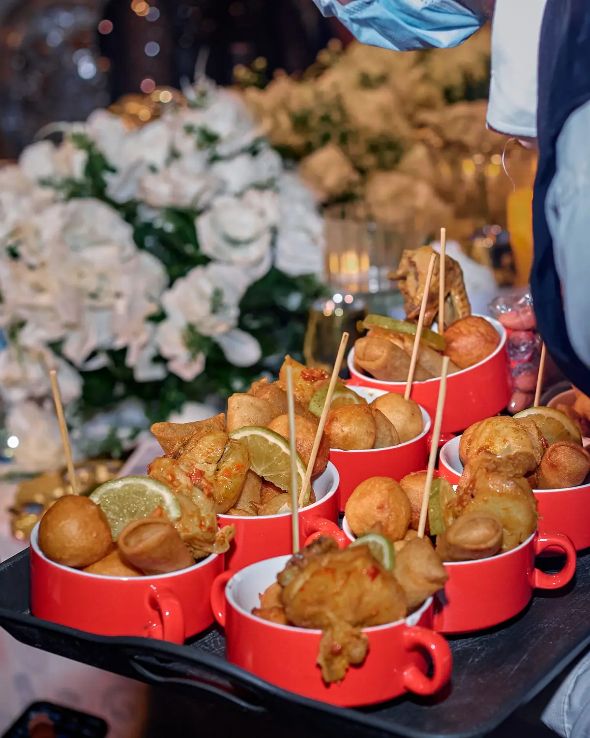 Small chops served in red bowls on a tray at a decorated event.