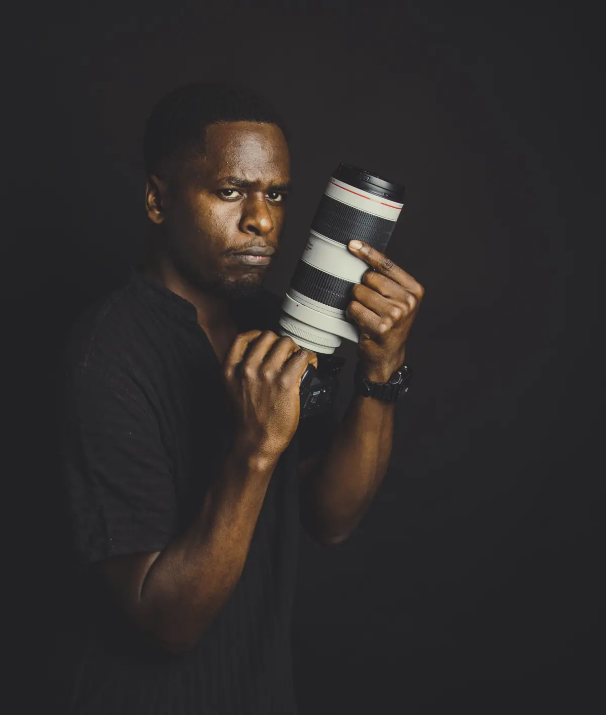 A photographer holding a camera and looking toward the lens.